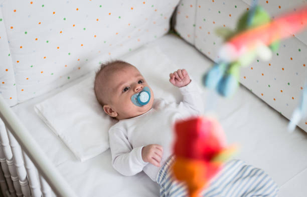 Handgemachte Babygeschenke/ Mobiles aus Filz - Two months old baby boy lying in the white baby crib